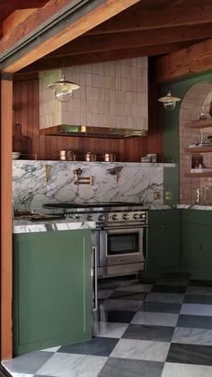 an open kitchen with green cabinets and marble counter tops on a checkered tile floor