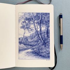 an open book with a pen on top of it next to a drawing of trees