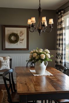 a dining room table with flowers in a vase on it and two chairs at the end