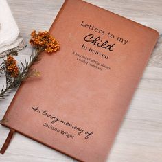 a brown book with writing on it sitting next to some flowers and a white towel