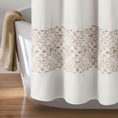 a white shower curtain with an intricate design on it's side and brown trim around the edge