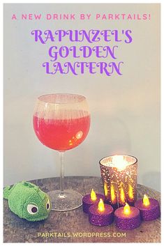 a table topped with candles next to a glass filled with liquid and a stuffed animal