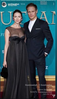 a man and woman standing next to each other on a red carpet