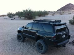 a black suv parked in the desert with its roof rack on it's flatbed