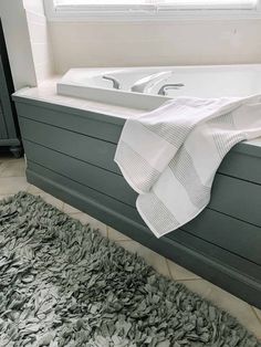 a white bath tub sitting on top of a rug next to a window with curtains