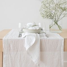 the table is set with white linens and flowers