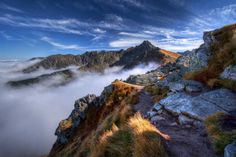 there is a trail going up the side of a mountain with clouds in the air