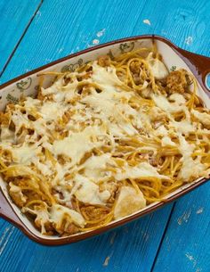 a casserole dish with meat and cheese in it on a blue wooden table