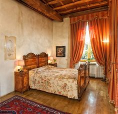 a bedroom with wooden floors and curtains on the windowsills is pictured in this image