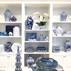 blue and white vases are on shelves in a room with other decorative items, such as flowers