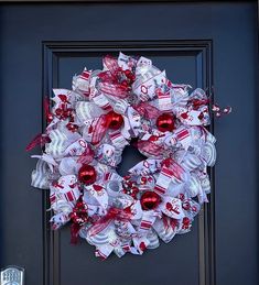 a red and white christmas wreath on a door