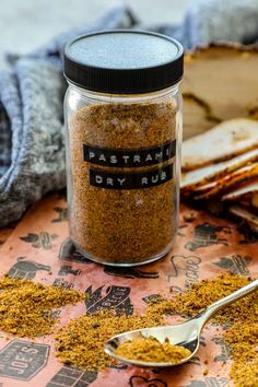 a jar filled with dry rubs sitting on top of a table next to a spoon