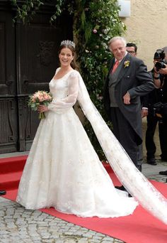 a woman in a white wedding dress standing on a red carpet