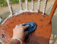 a person wiping up the rust on an old chair