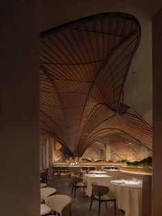 the interior of a restaurant with tables, chairs and an artistic design on the ceiling