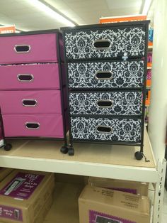 some pink and black drawers are sitting on the shelf in a store with other boxes