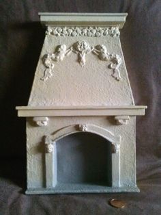 a white fireplace with carvings on the top and bottom part, in front of a black background