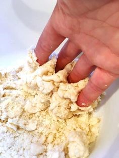 a hand is sprinkling flour into a white bowl