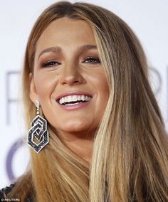 the blonde woman is smiling and wearing large earrings