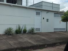 a white building with two garage doors and plants in front of it on the sidewalk