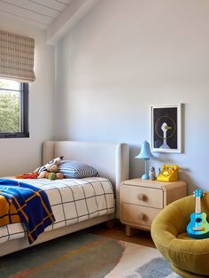 a bed room with a neatly made bed and a guitar