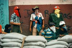 three men standing next to each other near bags of sandbags and burlocks