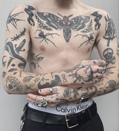 a man with many tattoos on his body and chest is holding his hands together in front of him