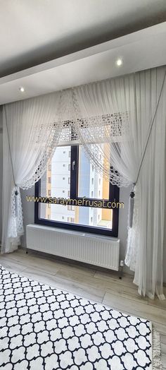 a living room with white drapes and black and white rugs on the floor