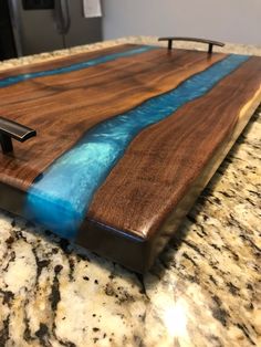 a wooden cutting board with blue water running down the side and two faucets on top