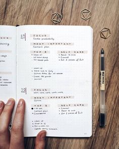 a person holding a pen and looking at an open notebook with some writing on it