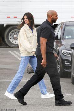 a man and woman walking across a parking lot