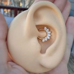 a person is holding an ear with a diamond ring in it's middle,