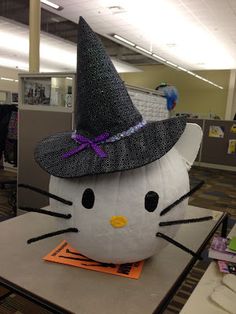 an inflatable hello kitty sitting on top of a table with a hat on it's head