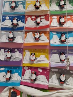 a bunch of cards with penguins on them hanging from the side of a wall together