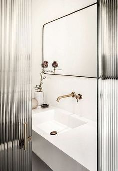 a bathroom sink sitting under a mirror next to a metal wall mounted faucet