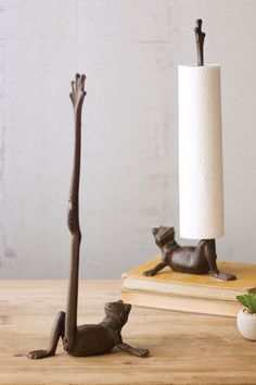 a cat figurine sitting on top of a wooden table next to a candle holder