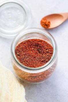 a glass jar filled with spices next to a wooden spoon