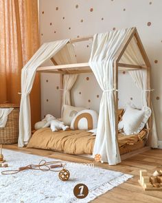 a child's bed with white drapes and polka dot wallpaper