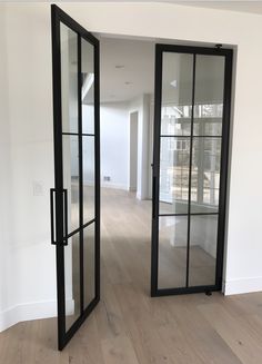 an empty room with glass doors and wood flooring in front of the door to another room