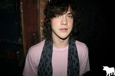 a young man with curly hair wearing a scarf