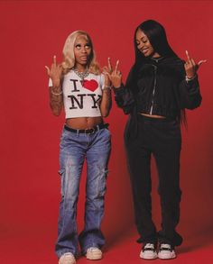 two women standing next to each other with their hands in the air and one holding up peace signs