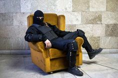 a person sitting in a chair with a black mask on