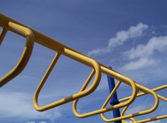 a yellow and blue metal rail with clouds in the background