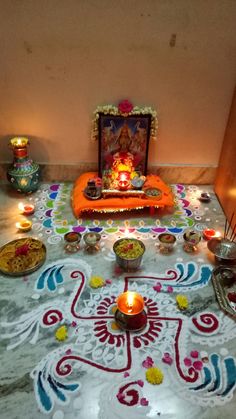 a decorated floor with candles and other items on it, in front of a wall