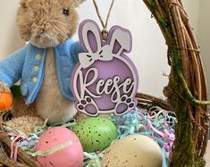 a teddy bear sitting in a basket filled with eggs and other items that include an easter bunny