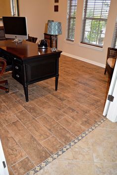 a computer desk sitting on top of a wooden table in a room with tile flooring