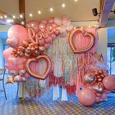 balloons and streamers in the shape of hearts are hanging on a wall at a party