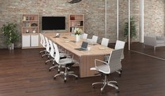 a large conference table with white chairs and a laptop on it in front of a brick wall