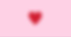 a blurry image of a red heart on a pink background