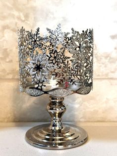 a silver candle holder with snowflakes on it